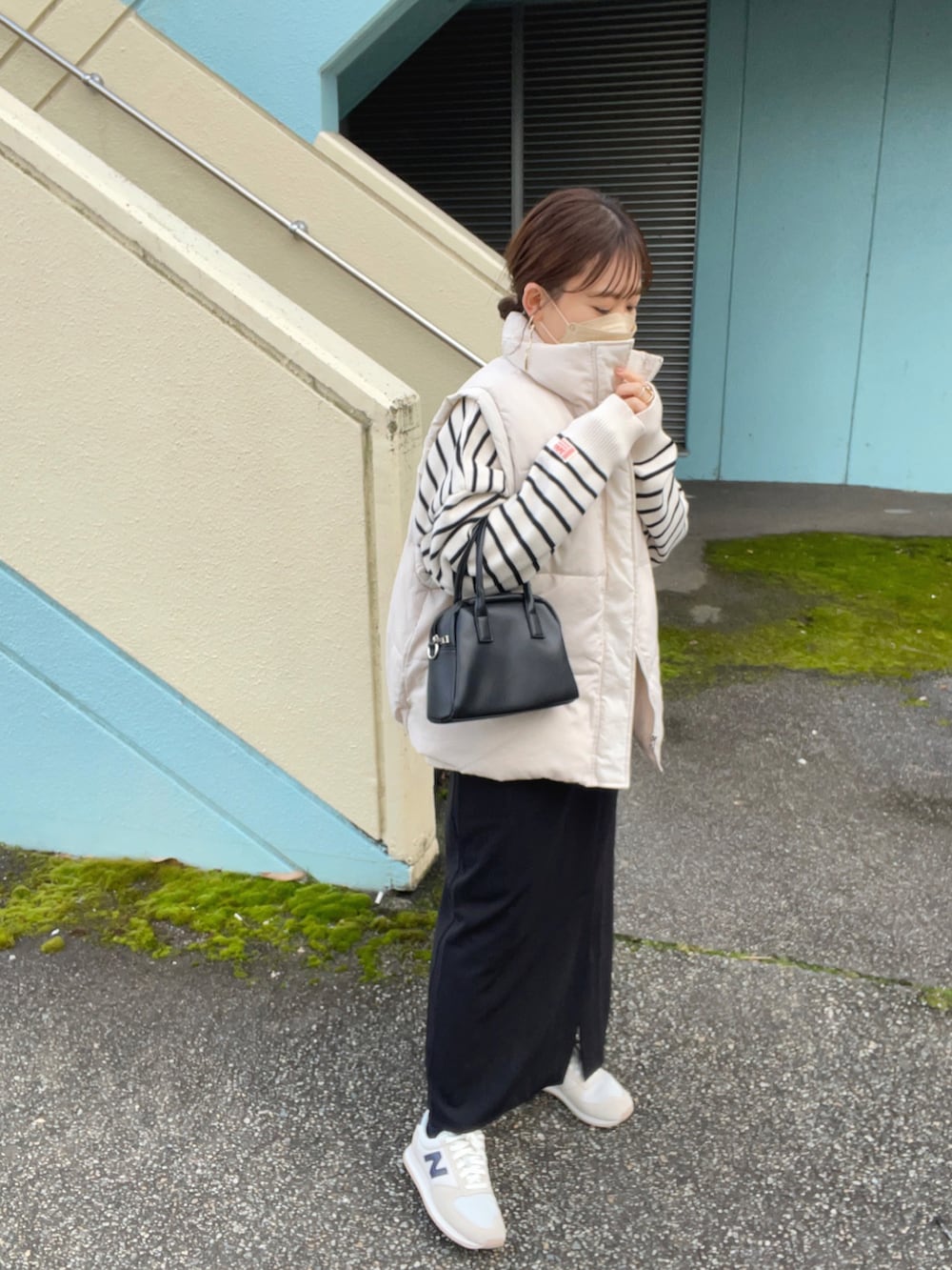 ホワイト系のニット/セーター、ホワイト系のダウンベスト、ブラック系のスカートを着用したレディースの冬コーディネートの5枚目の写真