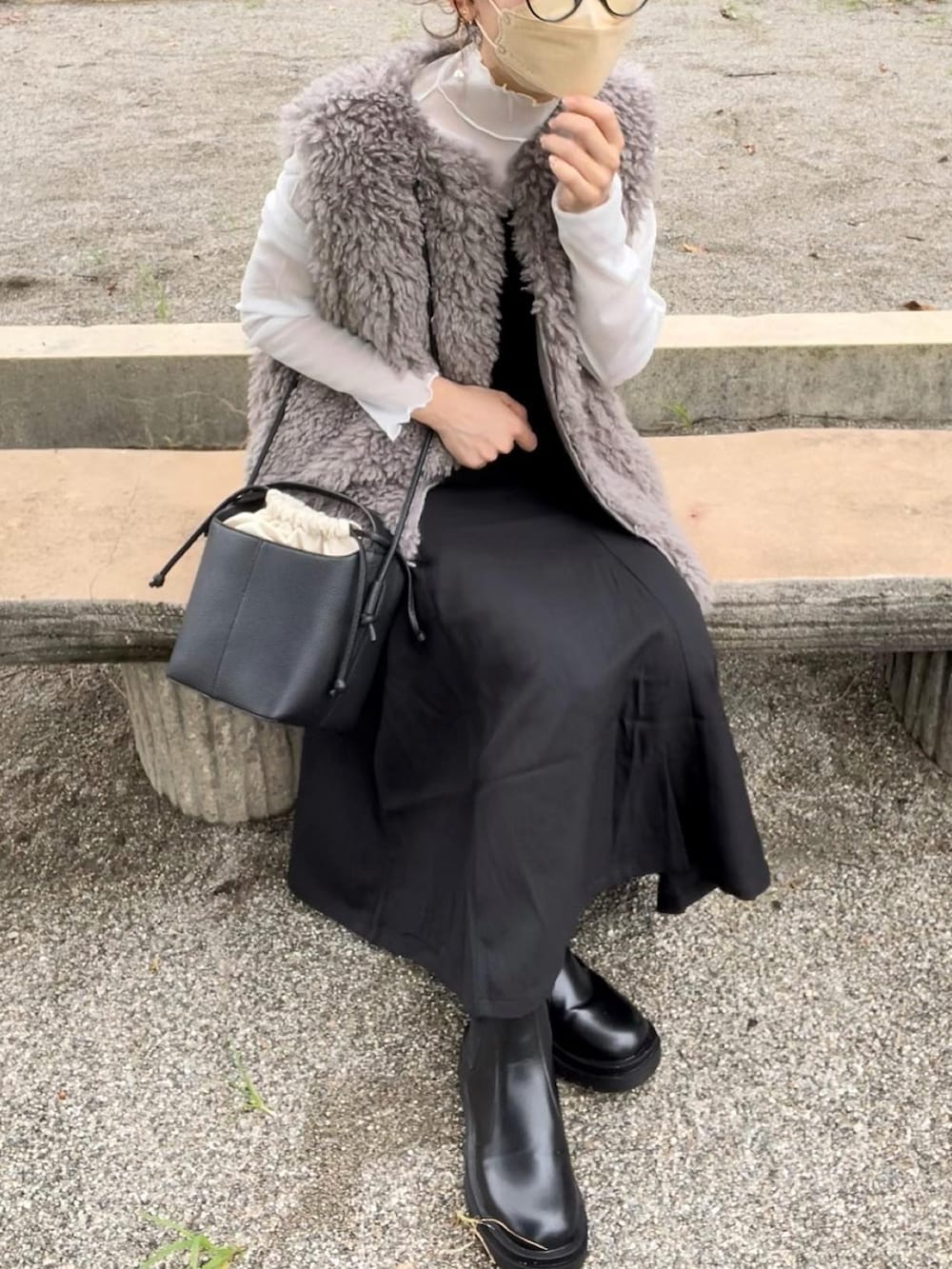 ベージュ系のベスト、ホワイト系のTシャツ/カットソー、ブラック系のジャンパースカートを着用したレディースの秋コーディネートの3枚目の写真