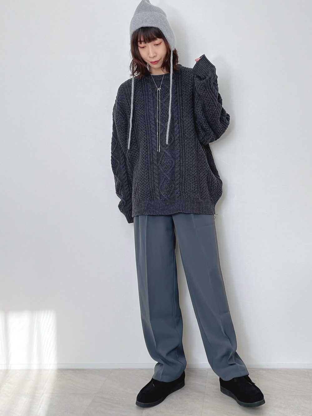 グレー系のニット/セーター、グレー系のスラックス、ブラック系のモカシン/デッキシューズを着用したレディースの冬コーディネートの2枚目の写真