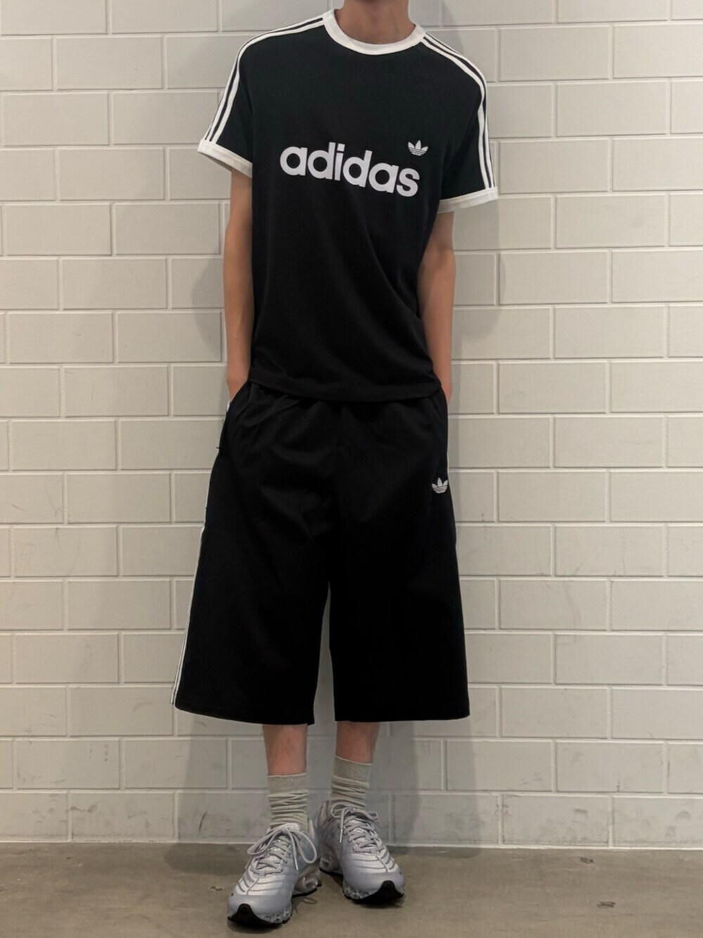 シルバー系のスニーカー、ブラック系のTシャツ/カットソー、ブラック系のその他パンツを着用したメンズの夏コーディネートの2枚目の写真