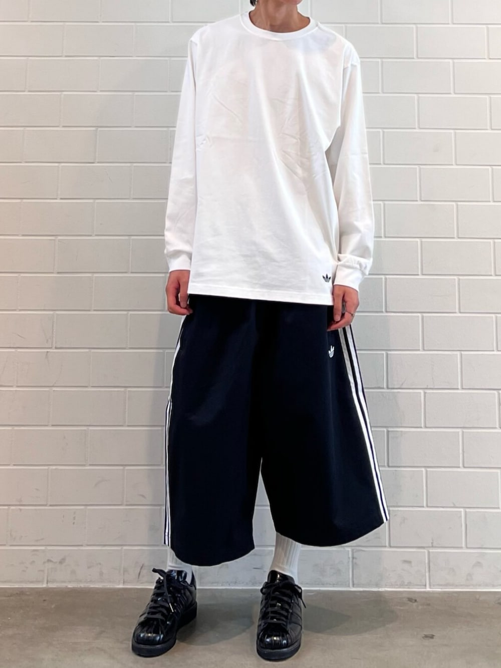 ブラック系のスニーカー、ホワイト系のTシャツ/カットソー、ブラック系のその他パンツを着用したメンズの夏コーディネートの2枚目の写真