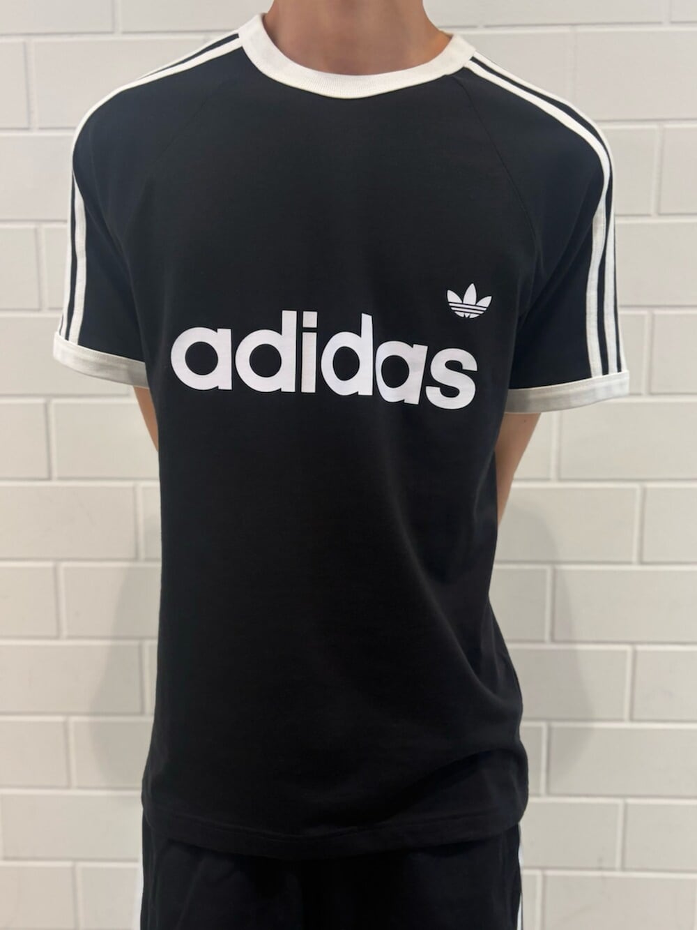 シルバー系のスニーカー、ブラック系のTシャツ/カットソー、ブラック系のその他パンツを着用したメンズの夏コーディネートの4枚目の写真