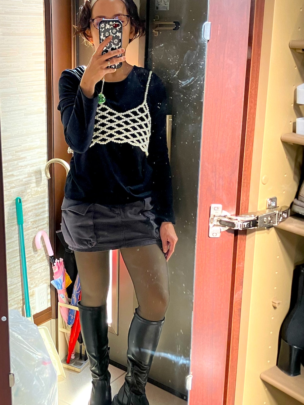 ホワイト系のベスト、ブラック系のブーツ、グレー系のデニムスカートを着用したレディースの春コーディネートの2枚目の写真