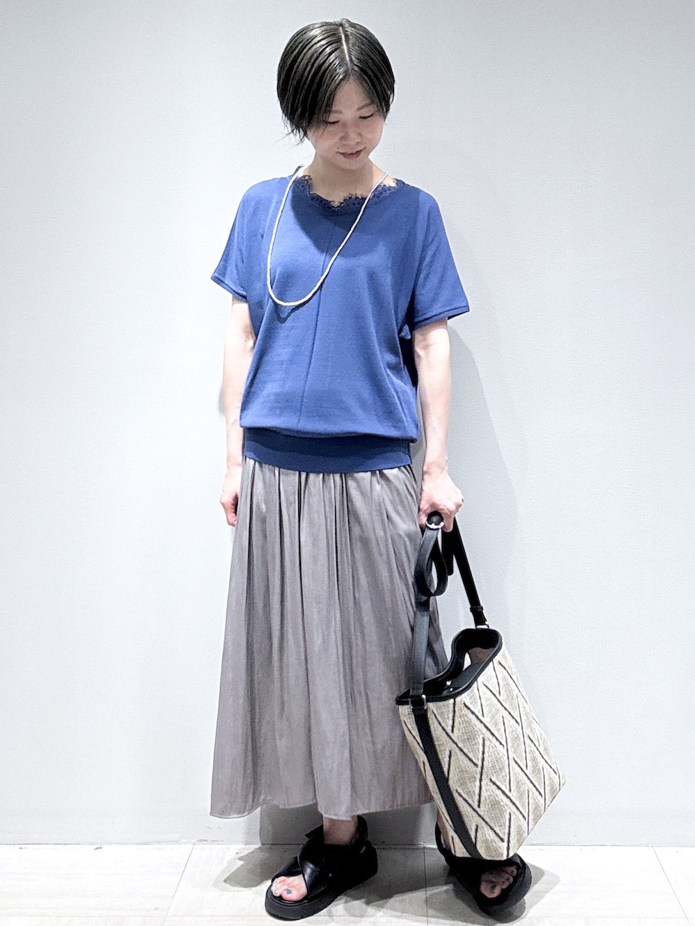 ブルー系のニット/セーター、ブラウン系のその他パンツ、ベージュ系のショルダーバッグを着用したレディースの夏コーディネートの2枚目の写真