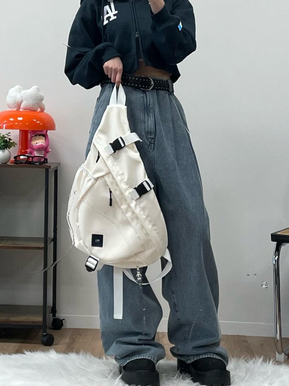 ブルー系のデニムパンツ、ホワイト系のボディバッグ/ウエストポーチ、ブラック系のブーツを着用したレディースの冬コーディネートの2枚目の写真