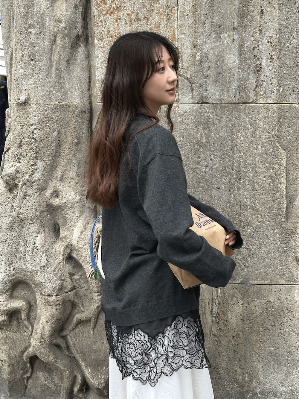 グレー系のニット/セーター、ホワイト系のワンピース、ベージュ系のサンダルを着用したレディースの春コーディネートの2枚目の写真