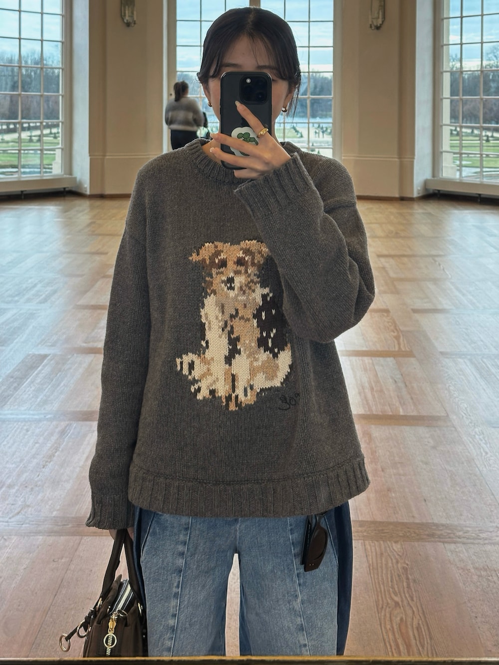 ブラウン系のトートバッグ、グレー系のニット/セーター、ブルー系のデニムパンツを着用したレディースの冬コーディネートの2枚目の写真