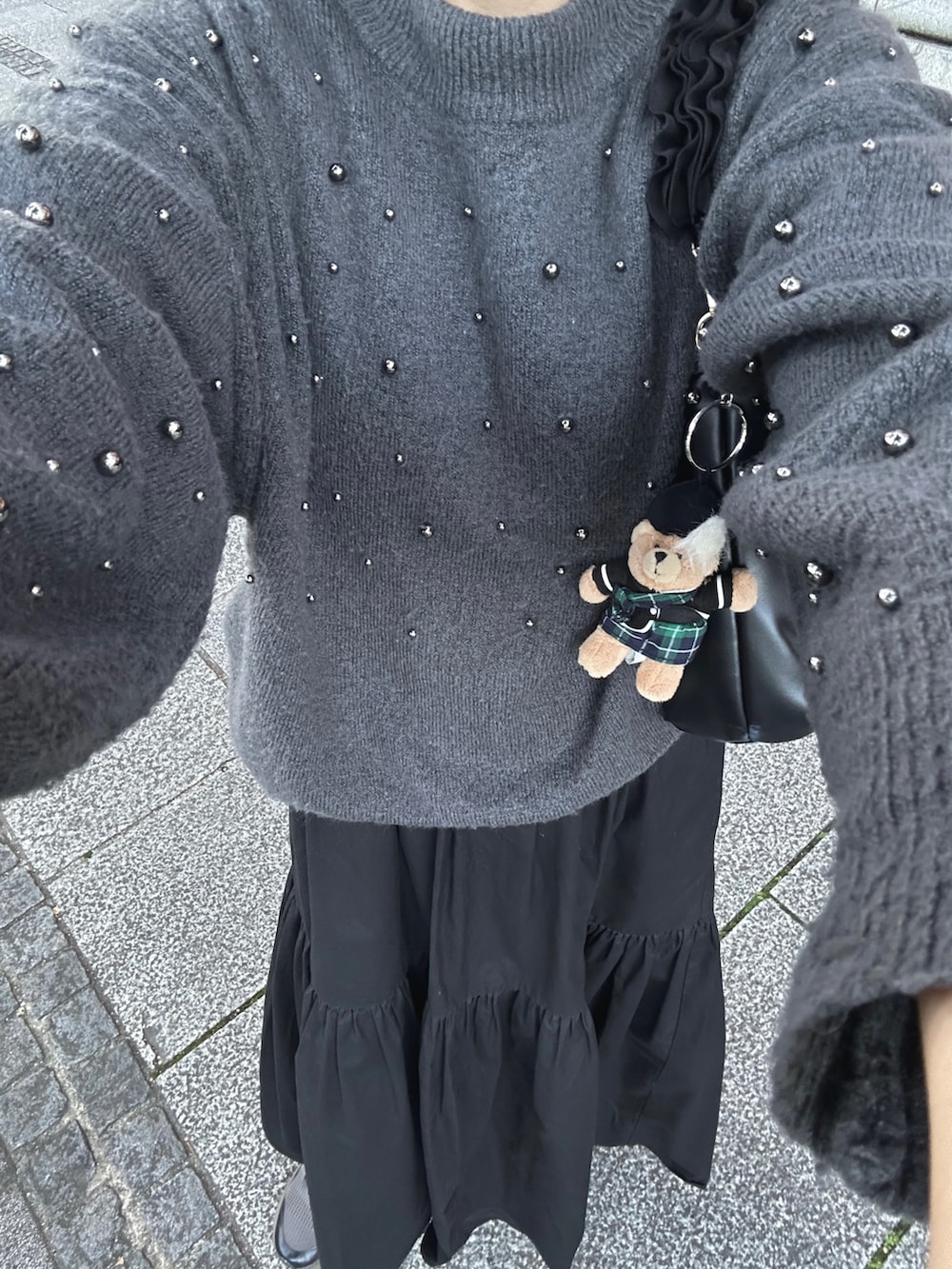 ブラック系のハンドバッグ、グレー系のニット/セーター、ブラック系のワンピースを着用したレディースの秋コーディネートの4枚目の写真