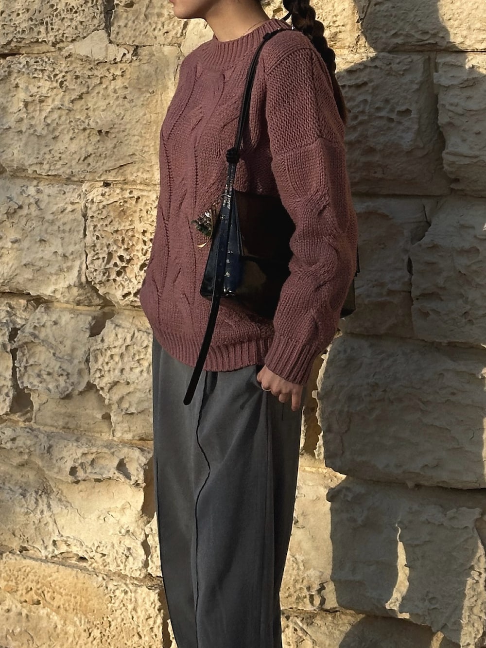 ピンク系のニット/セーター、ブラック系のハンドバッグ、ブラック系のスニーカーを着用したレディースの春コーディネートの2枚目の写真