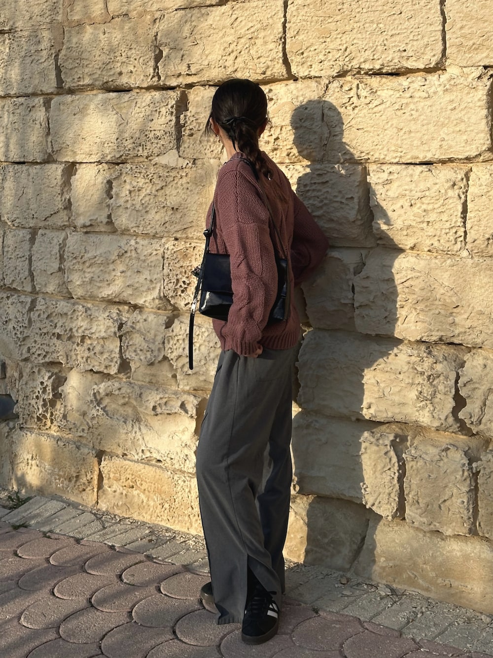 ピンク系のニット/セーター、ブラック系のハンドバッグ、ブラック系のスニーカーを着用したレディースの春コーディネートの3枚目の写真