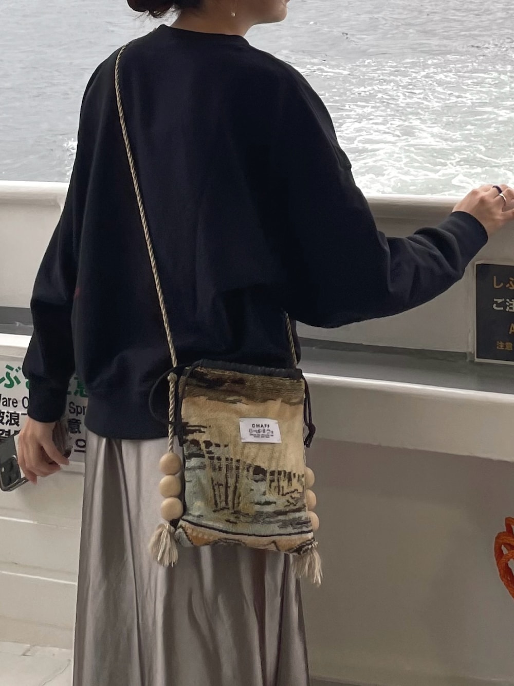 ブラック系のニット/セーター、ベージュ系のショルダーバッグ、グレー系のスニーカーを着用したレディースの秋コーディネートの4枚目の写真