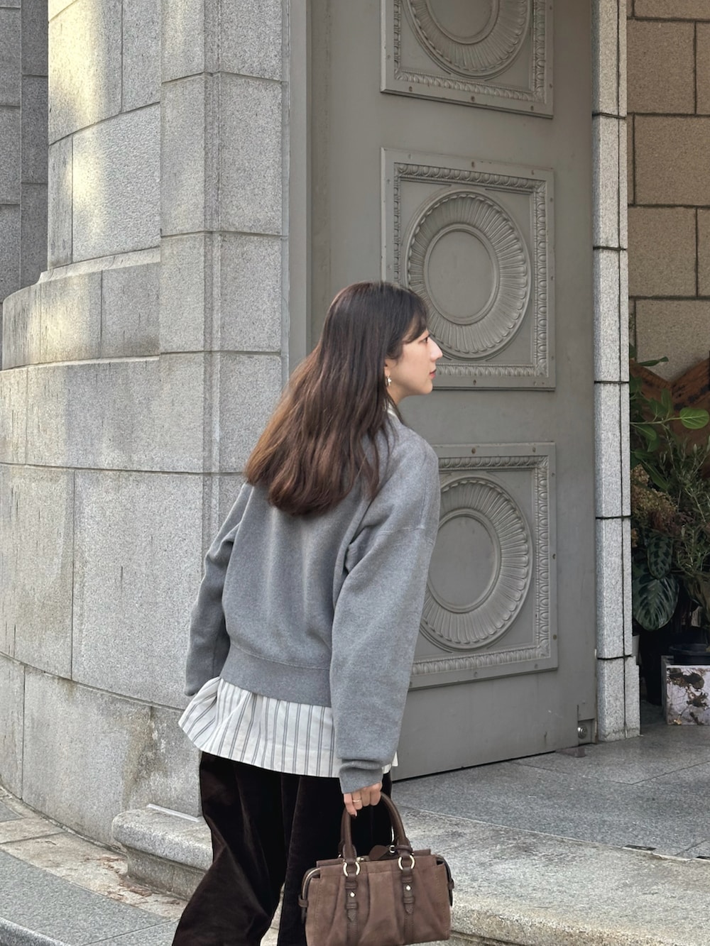 グレー系のニット/セーター、ホワイト系のシャツ/ブラウス、ブラウン系のその他パンツを着用したレディースの秋コーディネートの3枚目の写真