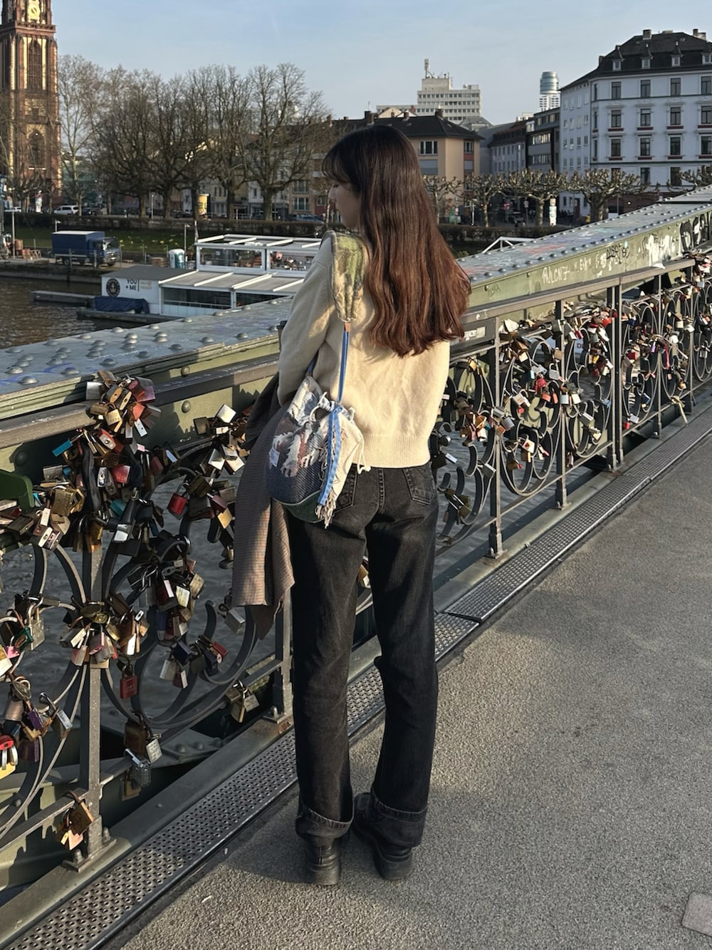 ブラック系のローファー、ホワイト系のニット/セーター、ブラック系のデニムパンツを着用したレディースの春コーディネートの4枚目の写真