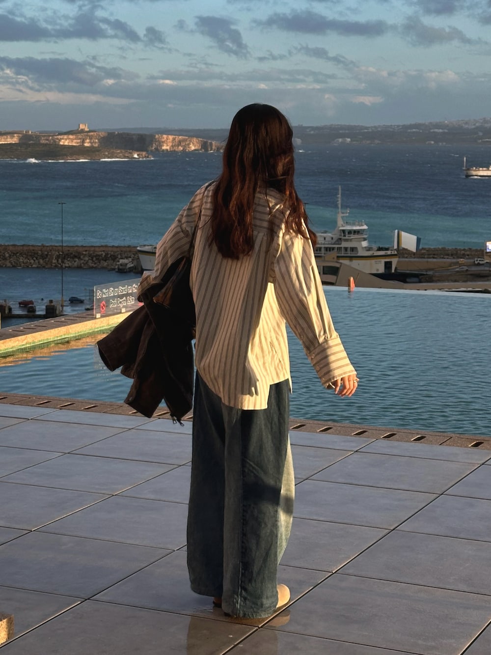 ホワイト系のシャツ/ブラウス、ブルー系のデニムパンツ、ベージュ系のサンダルを着用したレディースの冬コーディネートの3枚目の写真