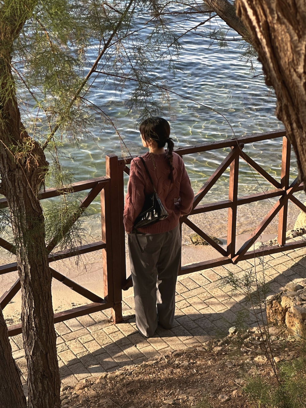 ピンク系のニット/セーター、ブラック系のハンドバッグ、ブラック系のスニーカーを着用したレディースの春コーディネートの5枚目の写真