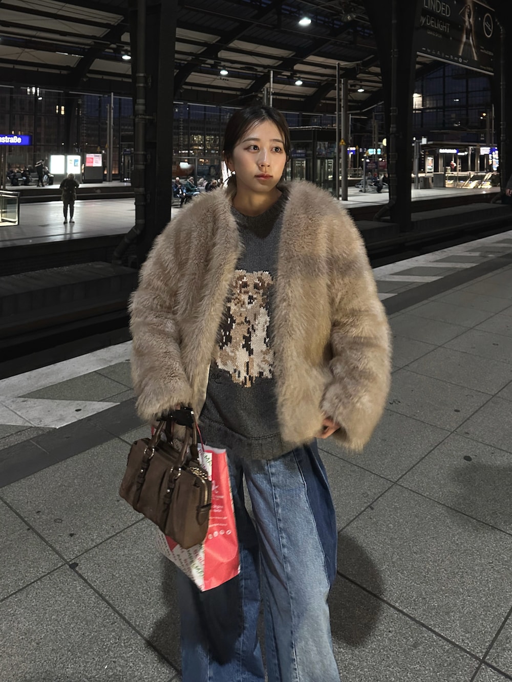 ブラウン系のトートバッグ、グレー系のニット/セーター、ブルー系のデニムパンツを着用したレディースの冬コーディネートの4枚目の写真