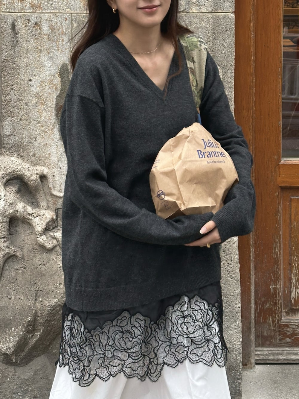 グレー系のニット/セーター、ホワイト系のワンピース、ベージュ系のサンダルを着用したレディースの春コーディネートの3枚目の写真