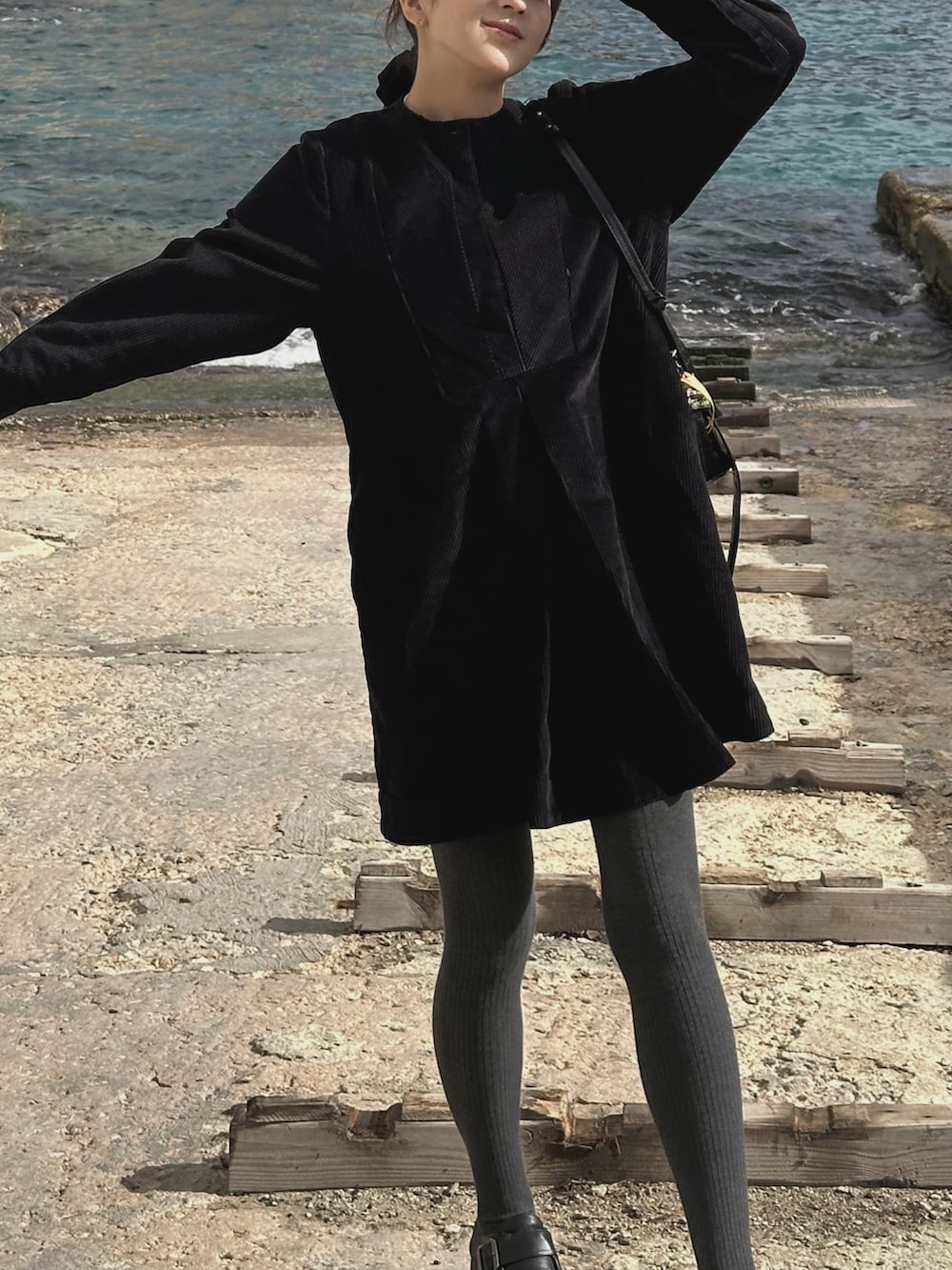 ブラック系のワンピース、ブラック系のハンドバッグ、ブラック系のローファーを着用したレディースの冬コーディネートの2枚目の写真