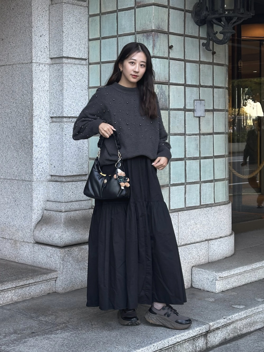 ブラック系のハンドバッグ、グレー系のニット/セーター、ブラック系のワンピースを着用したレディースの秋コーディネートの2枚目の写真