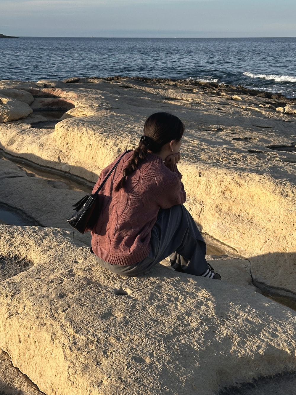 ピンク系のニット/セーター、ブラック系のハンドバッグ、ブラック系のスニーカーを着用したレディースの春コーディネートの4枚目の写真