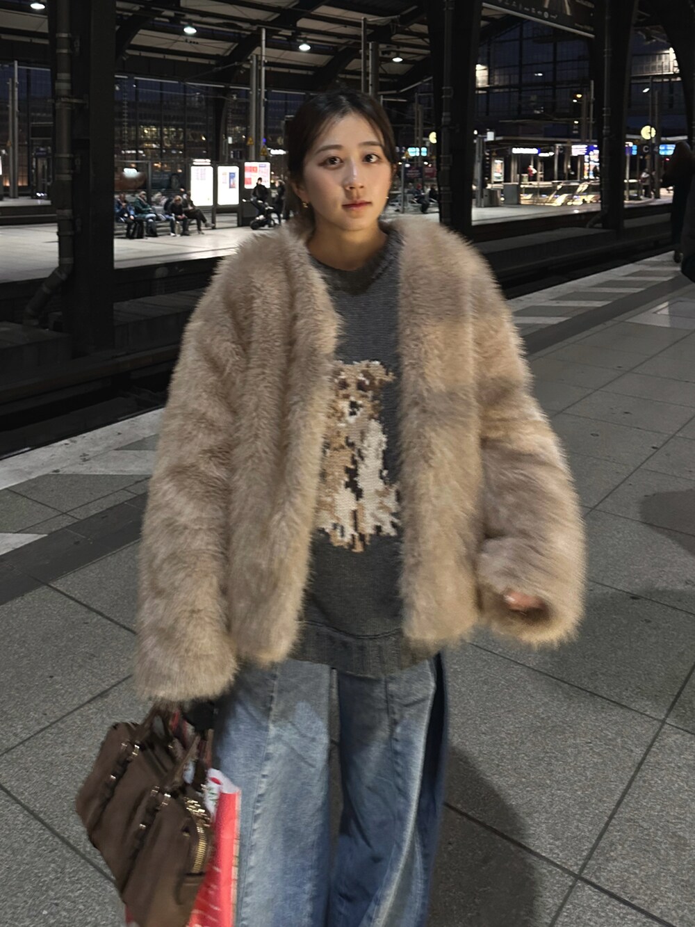 ブラウン系のトートバッグ、グレー系のニット/セーター、ブルー系のデニムパンツを着用したレディースの冬コーディネートの3枚目の写真