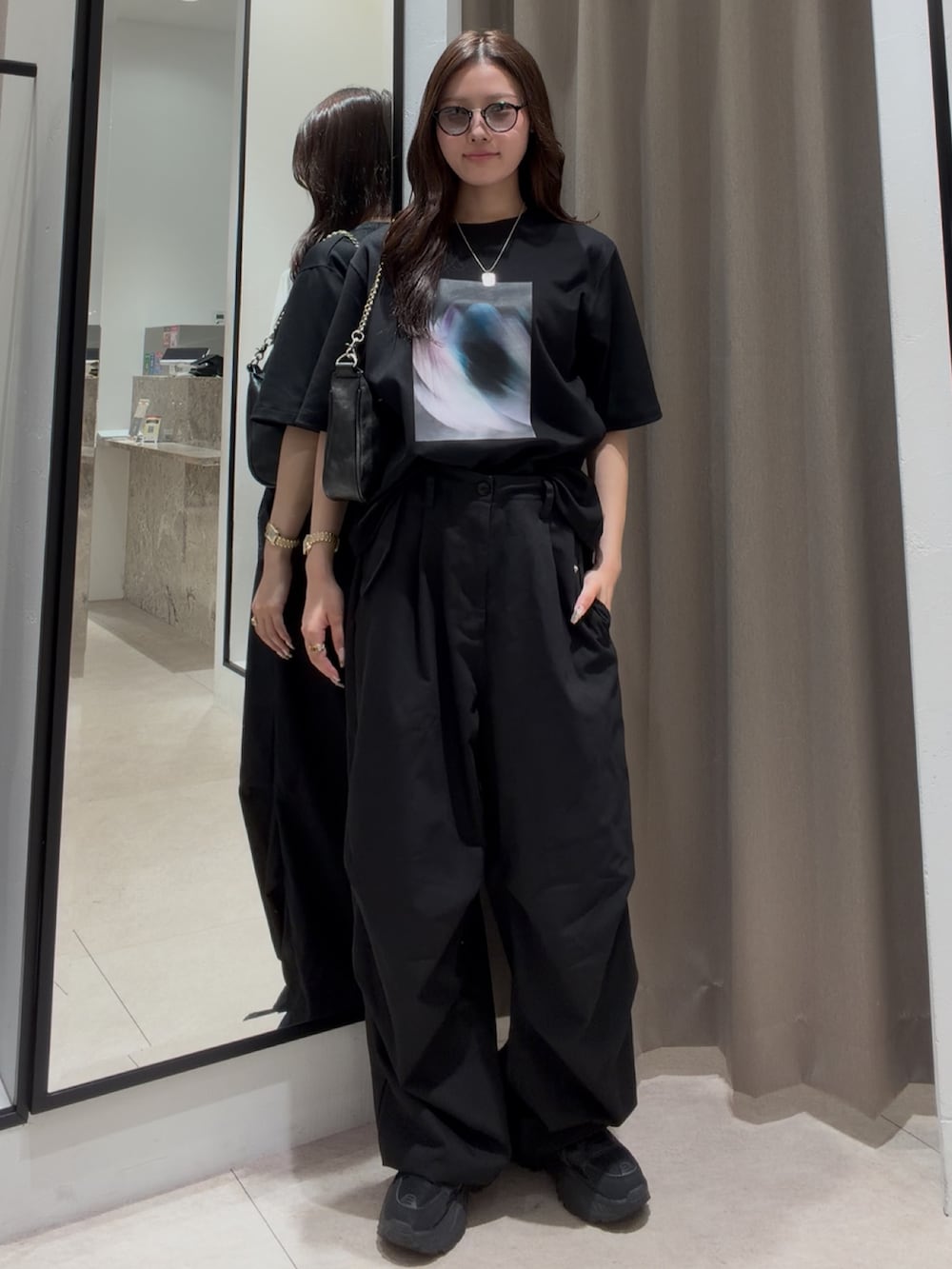 ブラック系のスラックス、ブラック系のTシャツ/カットソー、ブラック系のショルダーバッグを着用したレディースの夏コーディネートの2枚目の写真