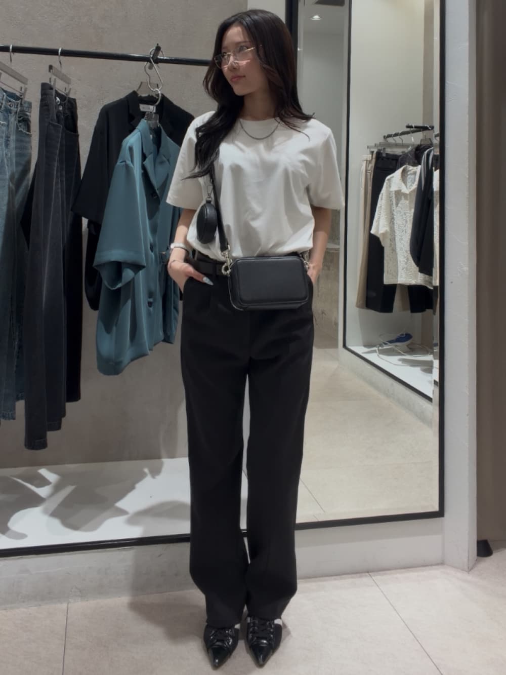 ブラック系のショルダーバッグ、ブラック系のスラックス、ホワイト系のTシャツ/カットソーを着用したレディースの春コーディネートの2枚目の写真