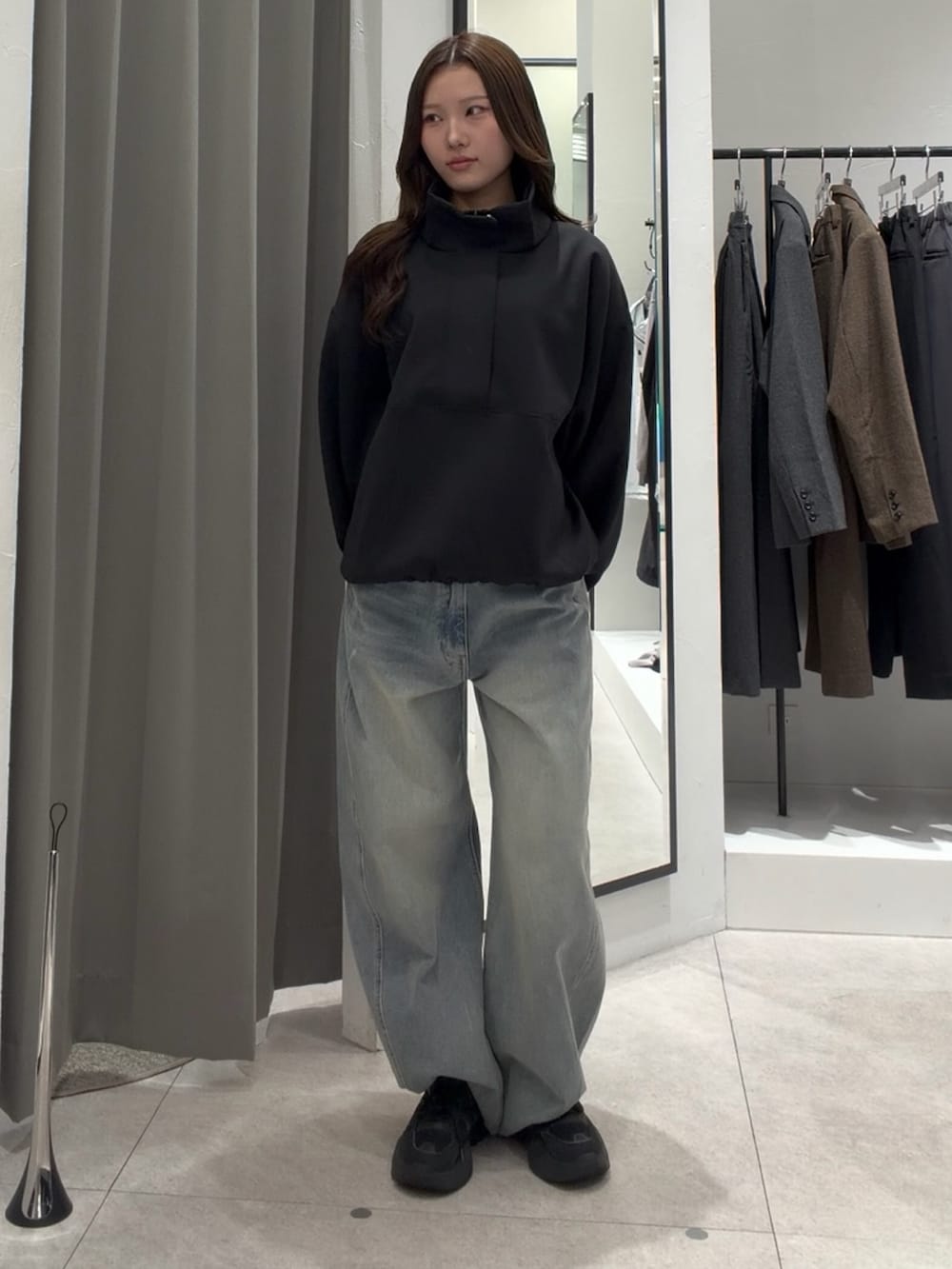 ブラック系のスウェット、ブルー系のデニムパンツ、ブラウン系のローファーを着用したレディースの秋コーディネートの2枚目の写真