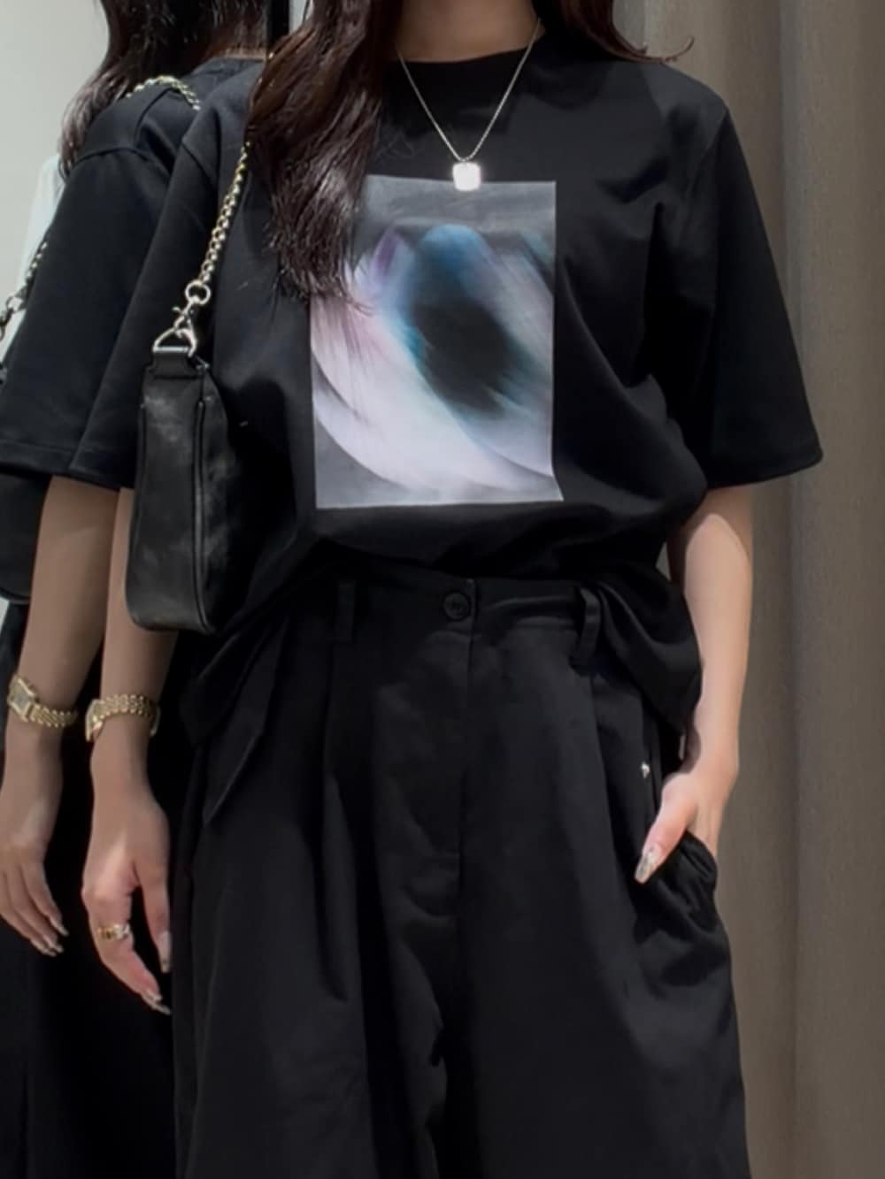 ブラック系のスラックス、ブラック系のTシャツ/カットソー、ブラック系のショルダーバッグを着用したレディースの夏コーディネートの4枚目の写真