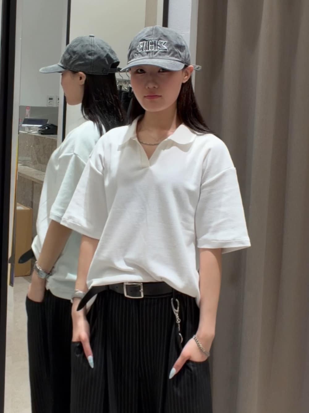 ブラック系のスラックス、ホワイト系のTシャツ/カットソー、ブラック系のキャップを着用したレディースの春コーディネートの6枚目の写真