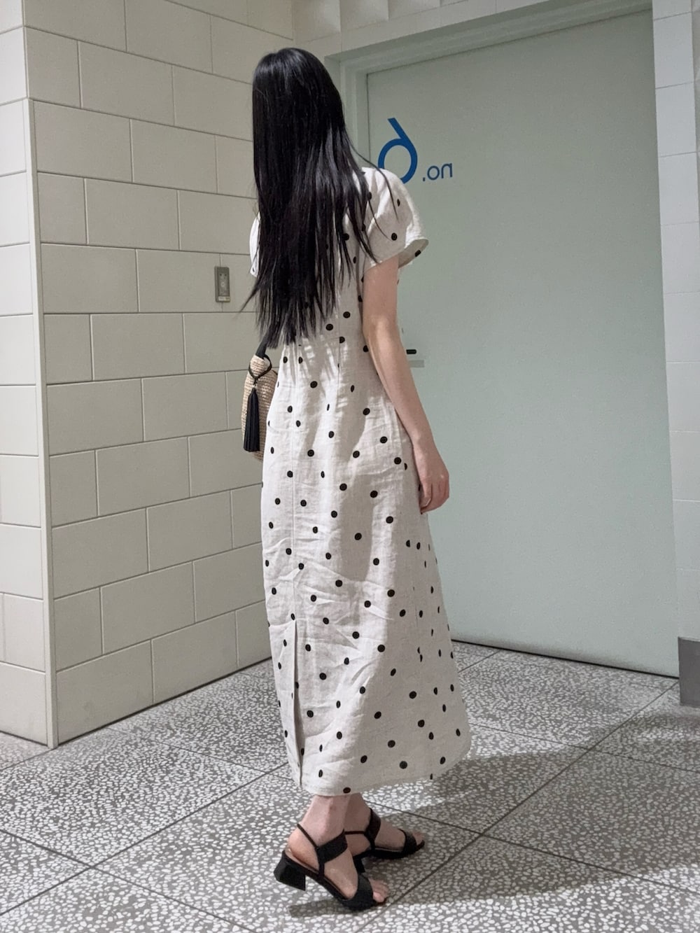 ベージュ系のワンピース、ブラック系のサンダル、ベージュ系のバッグを着用したレディースの夏コーディネートの3枚目の写真