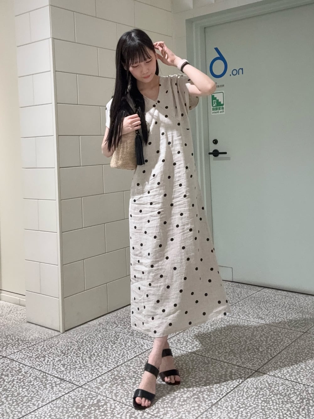 ベージュ系のワンピース、ブラック系のサンダル、ベージュ系のバッグを着用したレディースの夏コーディネートの2枚目の写真