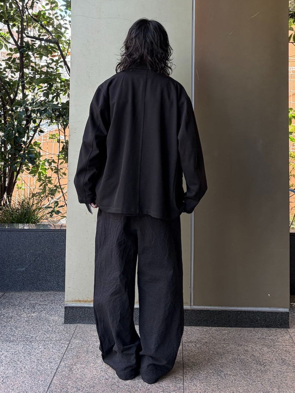 ブラック系のテーラードジャケット、ブラック系のスラックス、ブラック系のTシャツ/カットソーを着用したメンズの春コーディネートの3枚目の写真