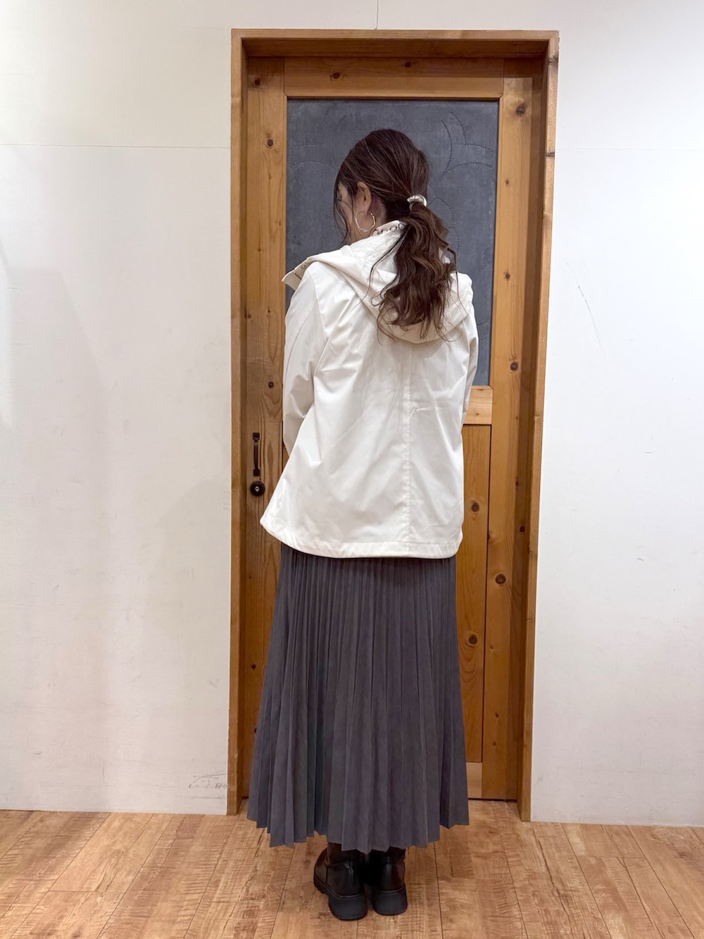 ホワイト系のブルゾン、グリーン系のニット/セーター、グレー系のスカートを着用したレディースの冬コーディネートの4枚目の写真