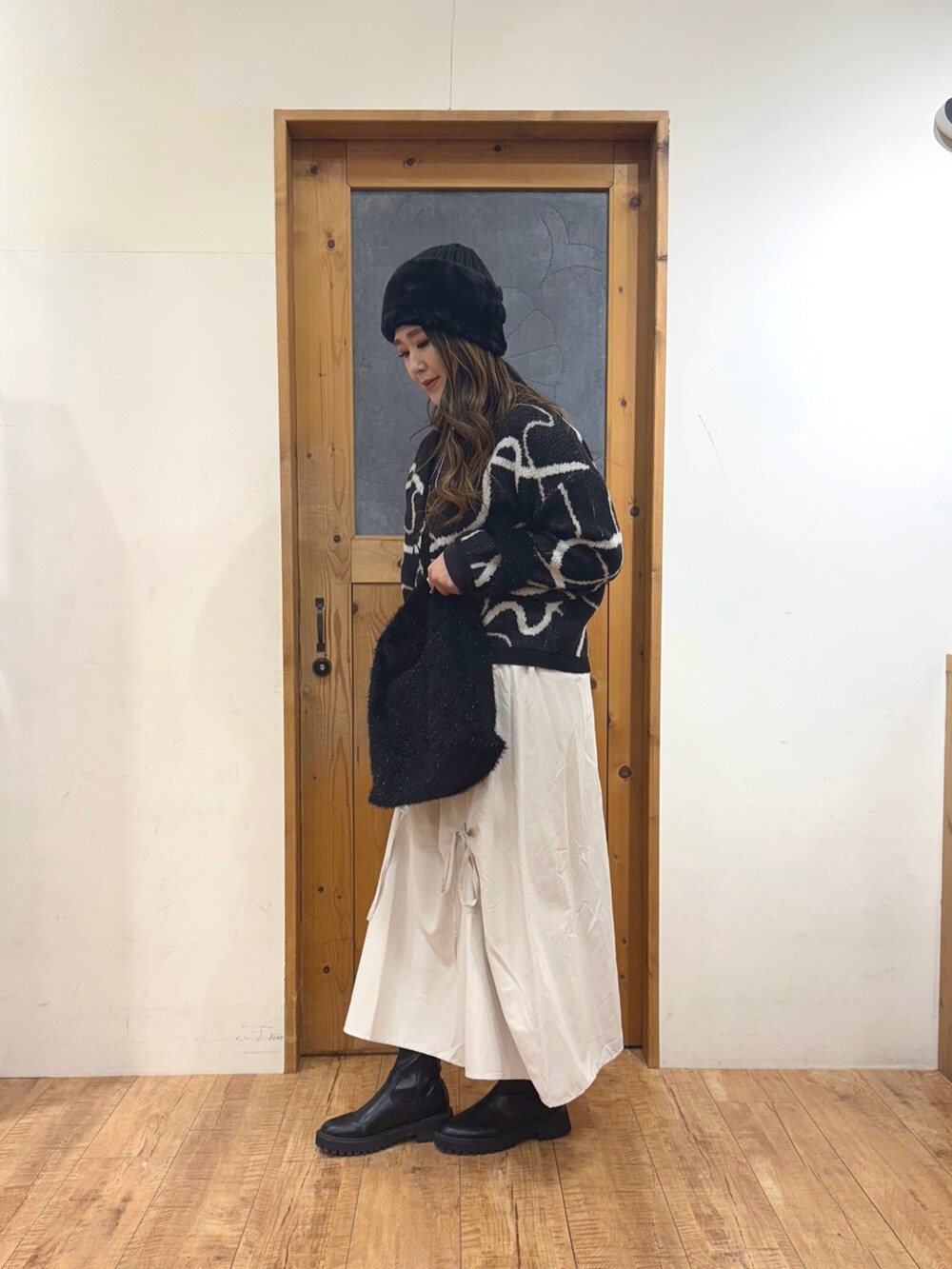 ホワイト系のスカート、ブラック系のトートバッグ、ブラック系のカーディガン/ボレロを着用したレディースの冬コーディネートの4枚目の写真