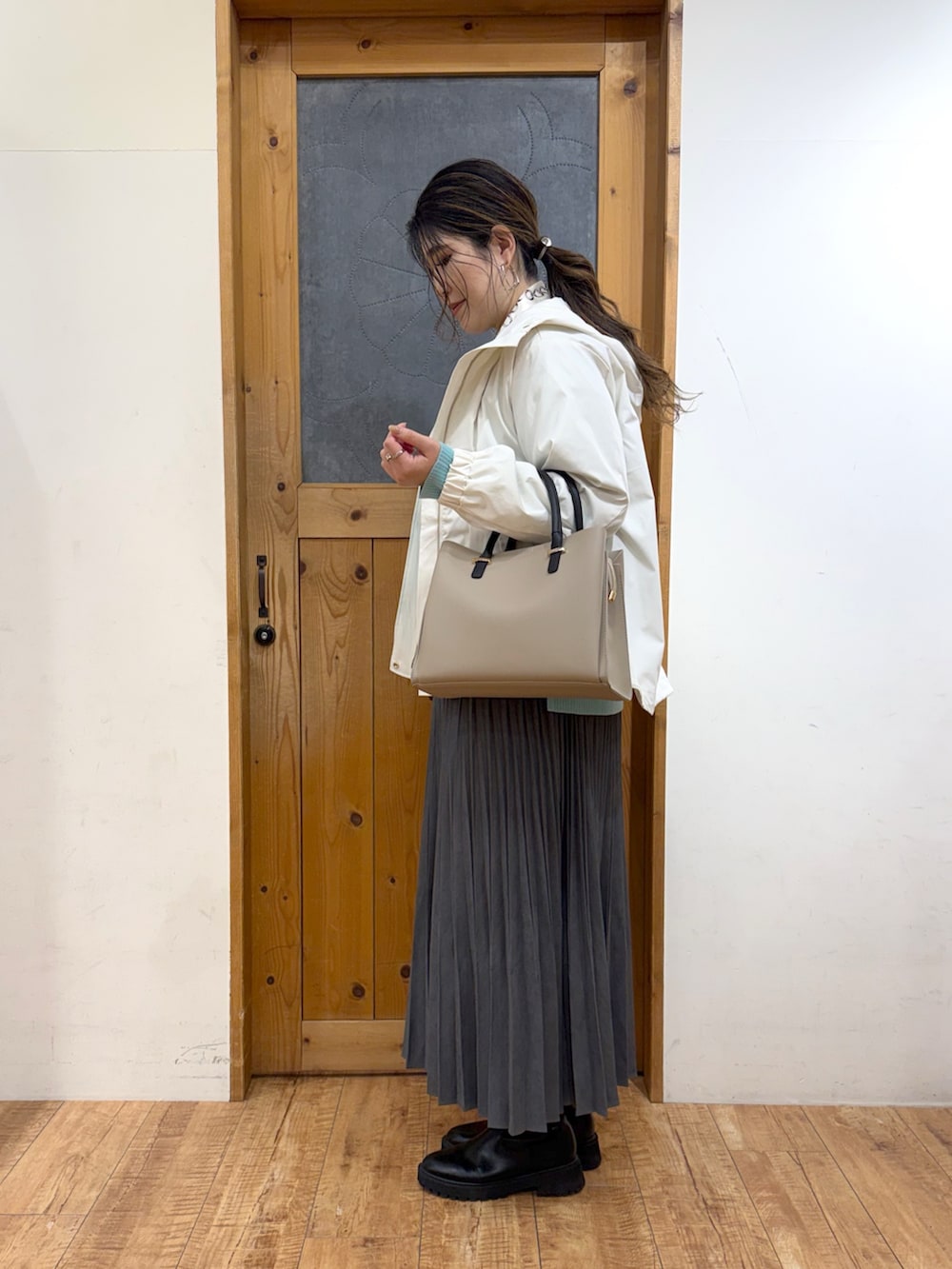 ホワイト系のブルゾン、グリーン系のニット/セーター、グレー系のスカートを着用したレディースの冬コーディネートの3枚目の写真