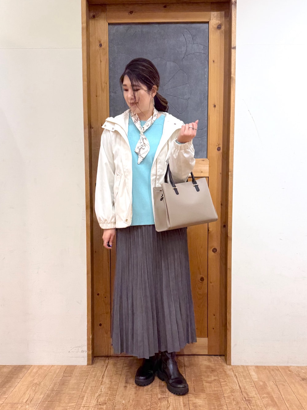 ホワイト系のブルゾン、グリーン系のニット/セーター、グレー系のスカートを着用したレディースの冬コーディネートの2枚目の写真
