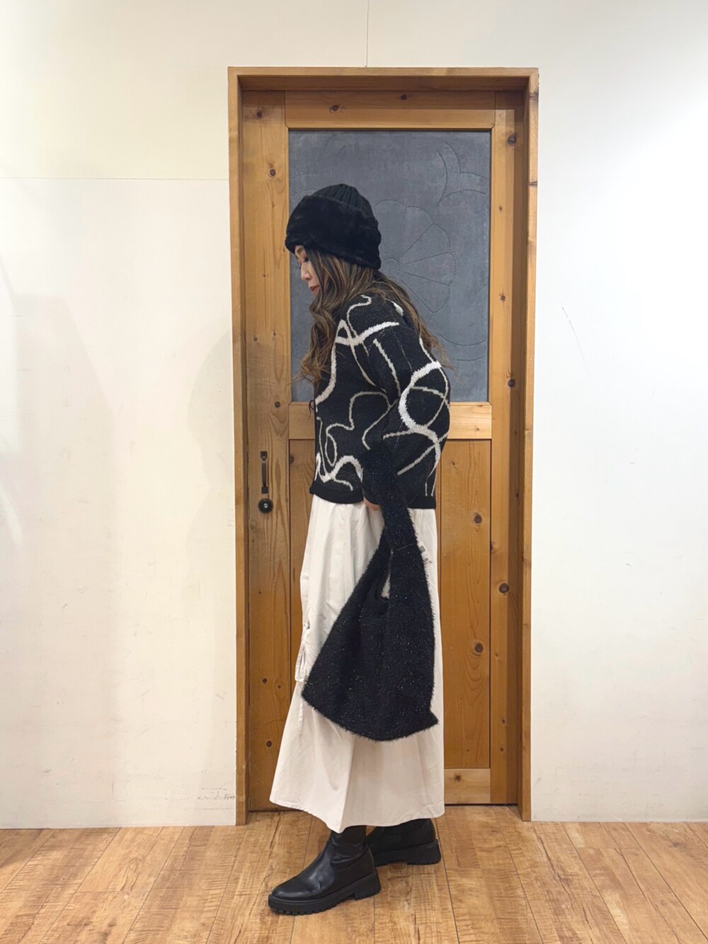 ホワイト系のスカート、ブラック系のトートバッグ、ブラック系のカーディガン/ボレロを着用したレディースの冬コーディネートの5枚目の写真