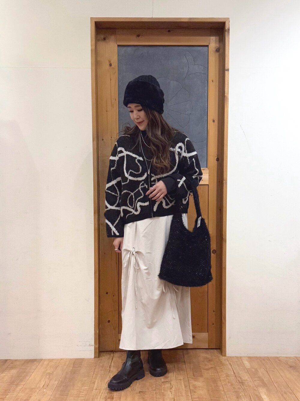 ホワイト系のスカート、ブラック系のトートバッグ、ブラック系のカーディガン/ボレロを着用したレディースの冬コーディネートの2枚目の写真