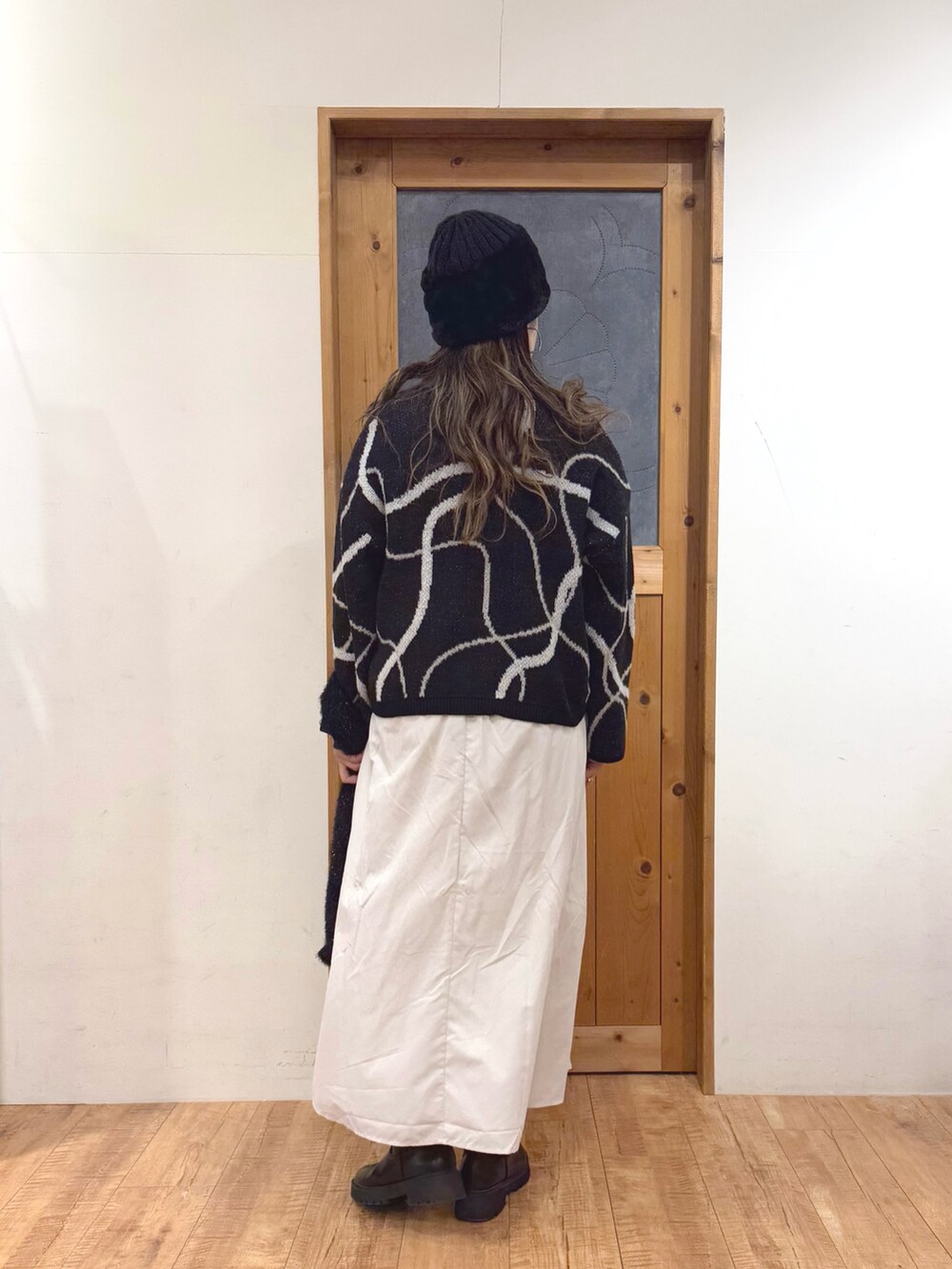 ホワイト系のスカート、ブラック系のトートバッグ、ブラック系のカーディガン/ボレロを着用したレディースの冬コーディネートの7枚目の写真