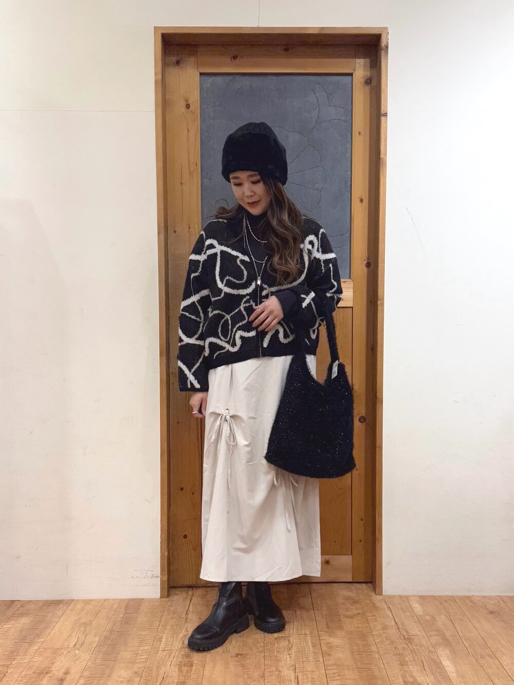 ホワイト系のスカート、ブラック系のトートバッグ、ブラック系のカーディガン/ボレロを着用したレディースの冬コーディネートの3枚目の写真