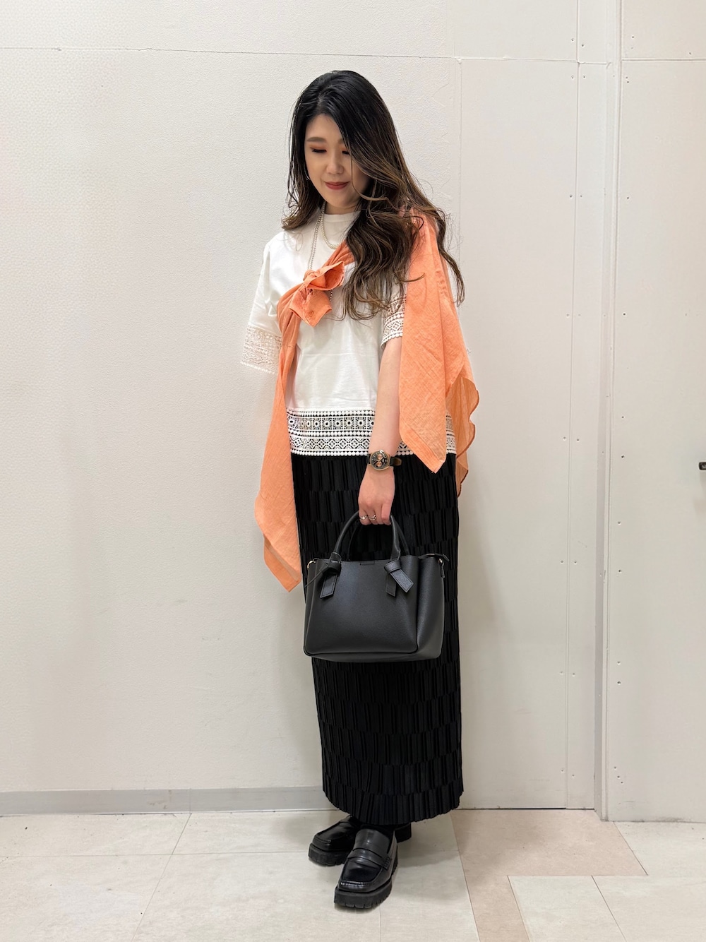 オレンジ系のシャツ/ブラウス、ホワイト系のTシャツ/カットソー、ブラック系のスカートを着用したレディースの春コーディネートの3枚目の写真