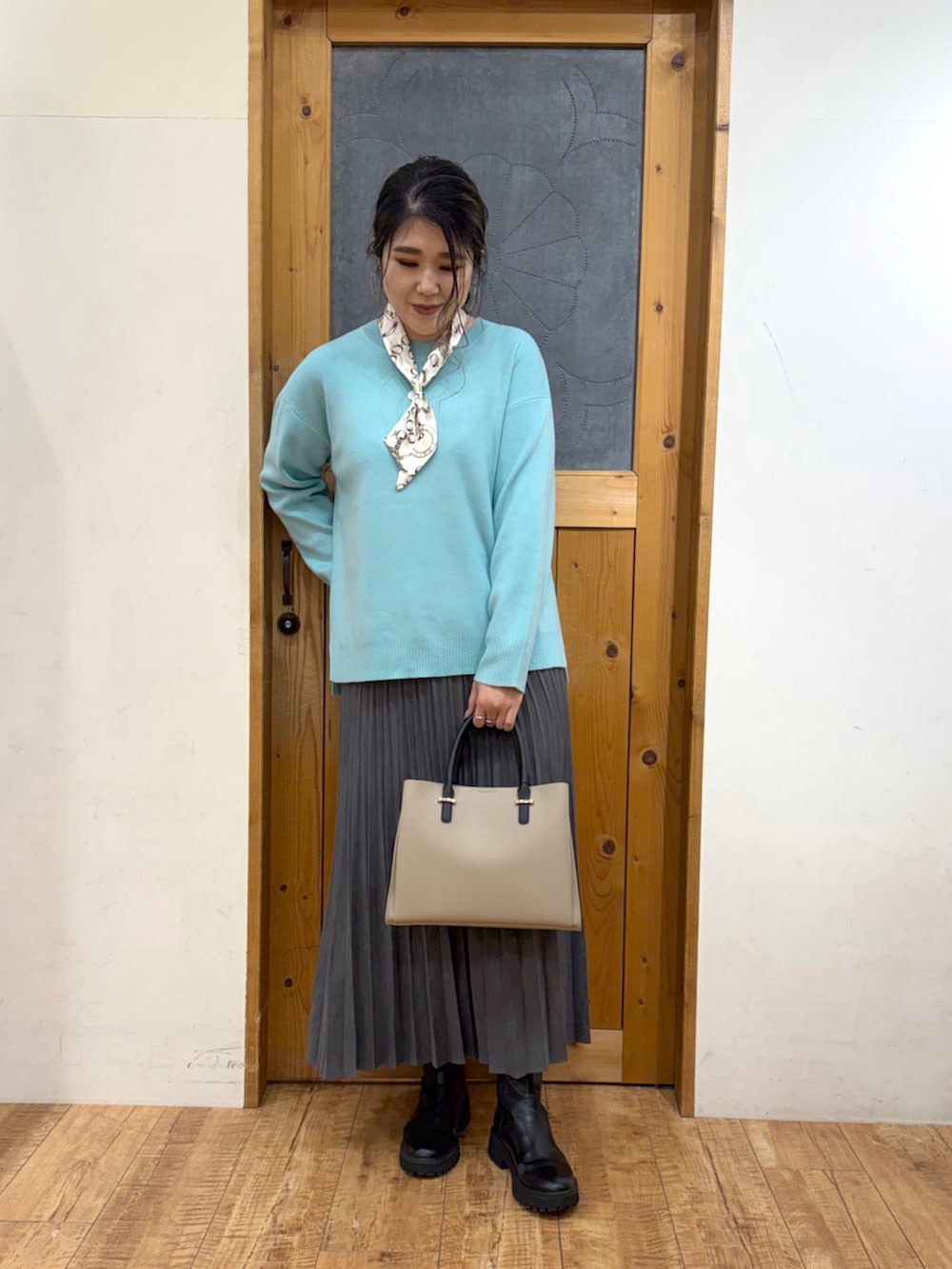 ホワイト系のブルゾン、グリーン系のニット/セーター、グレー系のスカートを着用したレディースの冬コーディネートの6枚目の写真