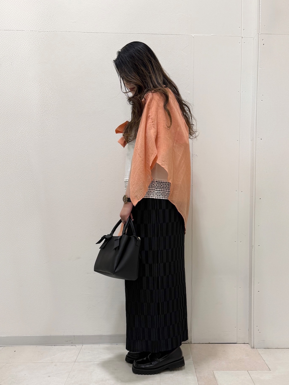 オレンジ系のシャツ/ブラウス、ホワイト系のTシャツ/カットソー、ブラック系のスカートを着用したレディースの春コーディネートの4枚目の写真