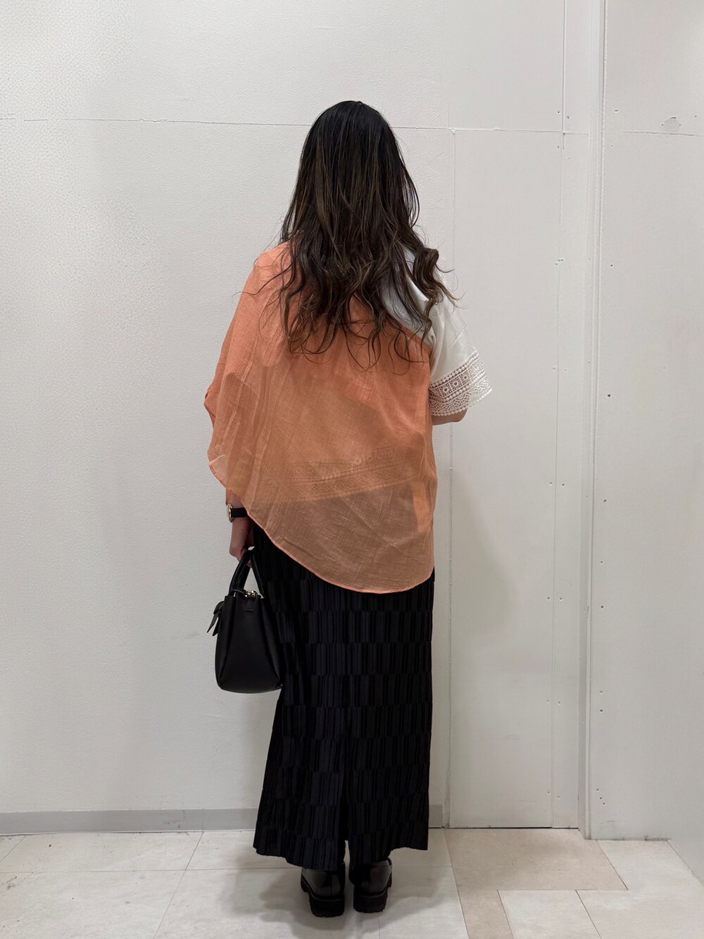 オレンジ系のシャツ/ブラウス、ホワイト系のTシャツ/カットソー、ブラック系のスカートを着用したレディースの春コーディネートの5枚目の写真