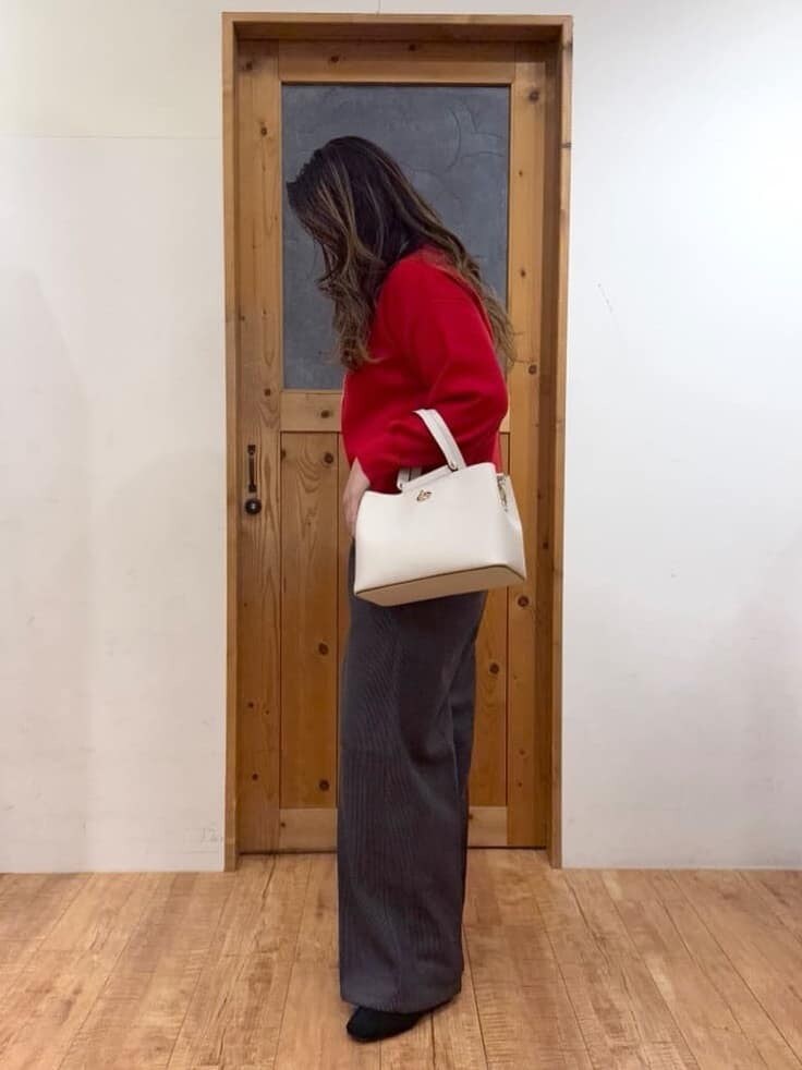 レッド系のニット/セーター、グレー系のその他パンツ、ブラック系のブーツを着用したレディースの秋コーディネートの2枚目の写真