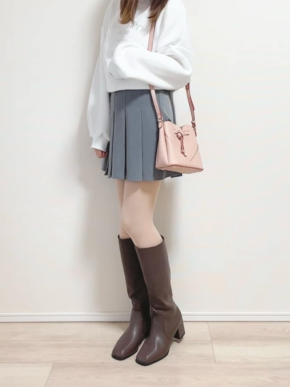 ホワイト系のスウェット、ピンク系のショルダーバッグ、グレー系のスカートを着用したレディースの冬コーディネートの2枚目の写真