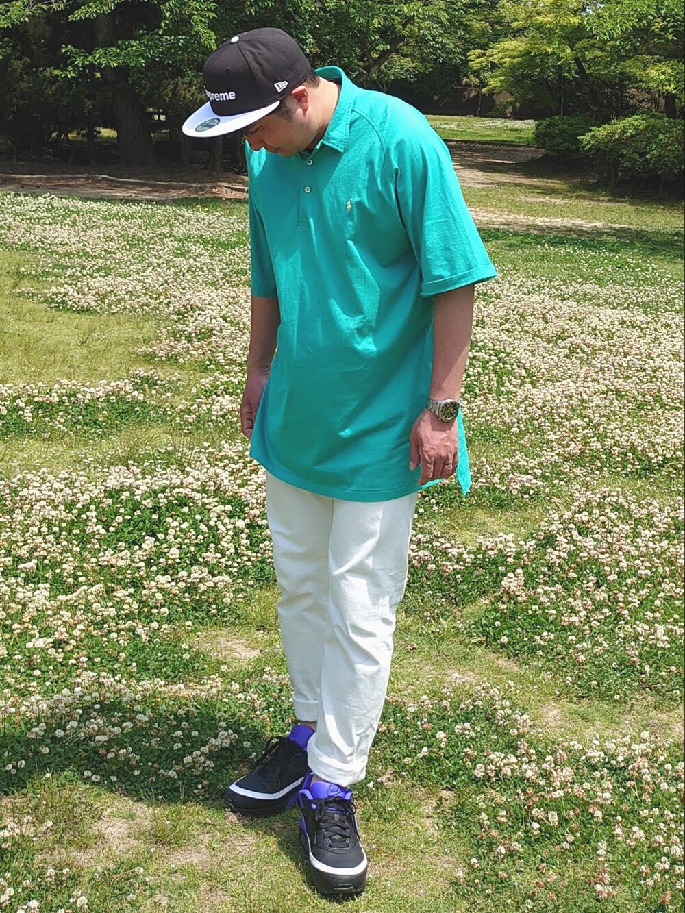 グリーン系のポロシャツ、ホワイト系のデニムパンツ、ブラック系のスニーカーを着用したメンズの春コーディネートの4枚目の写真