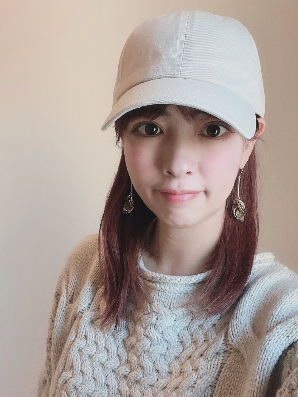 ベージュ系のニット/セーター、ホワイト系のスカート、ホワイト系のスニーカーを着用したレディースの春コーディネートの2枚目の写真