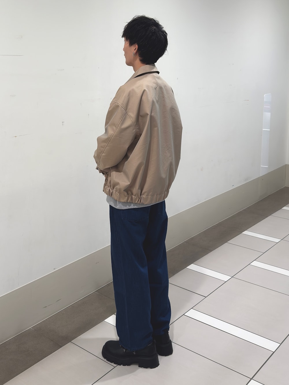 ベージュ系のブルゾン、グレー系のスウェット、ブルー系のデニムパンツを着用したメンズの冬コーディネートの2枚目の写真